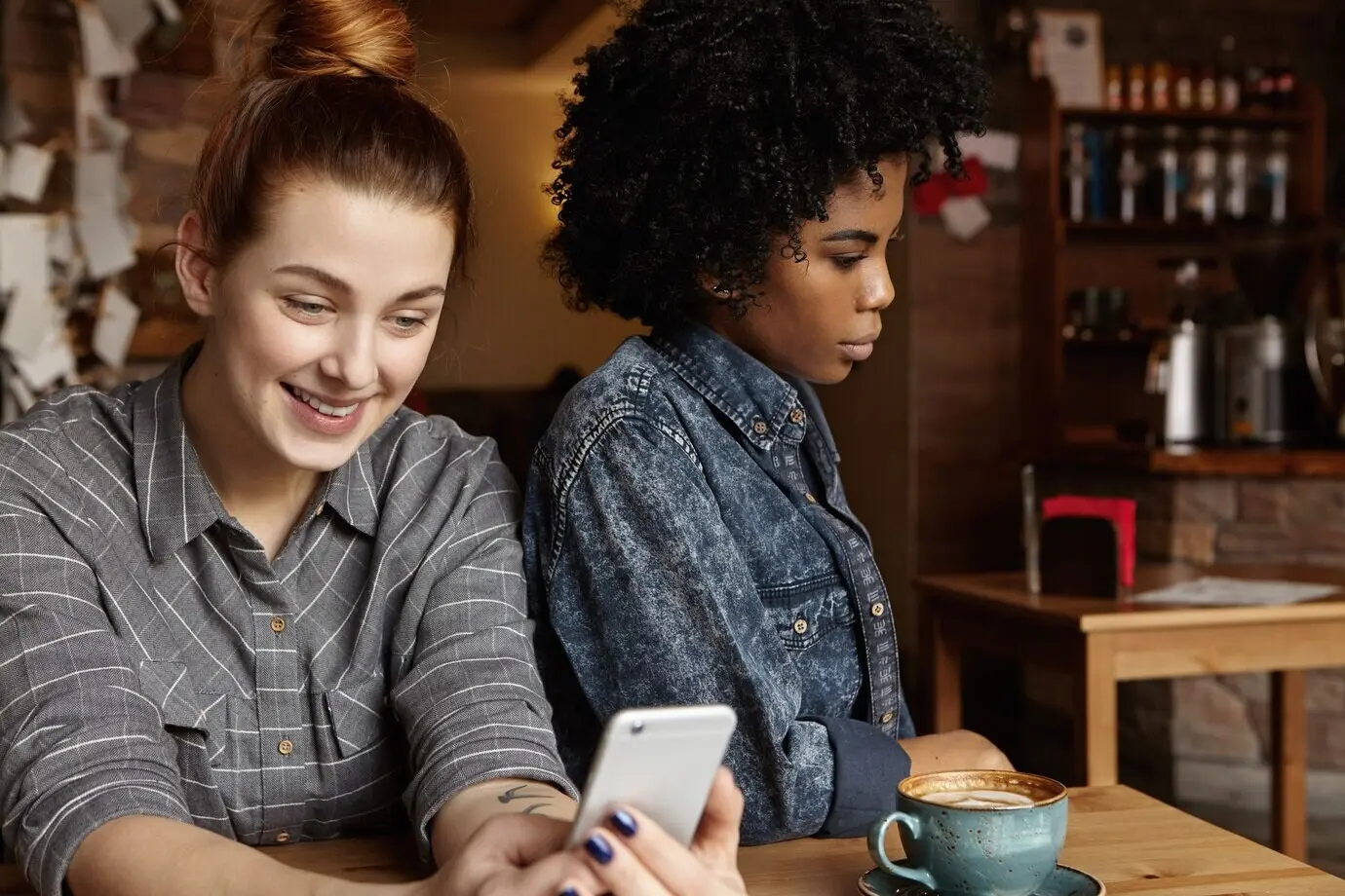 Mujer caucásica atractiva y feliz con el cabello recogido en un moño que envía mensajes en línea a través de las redes sociales.