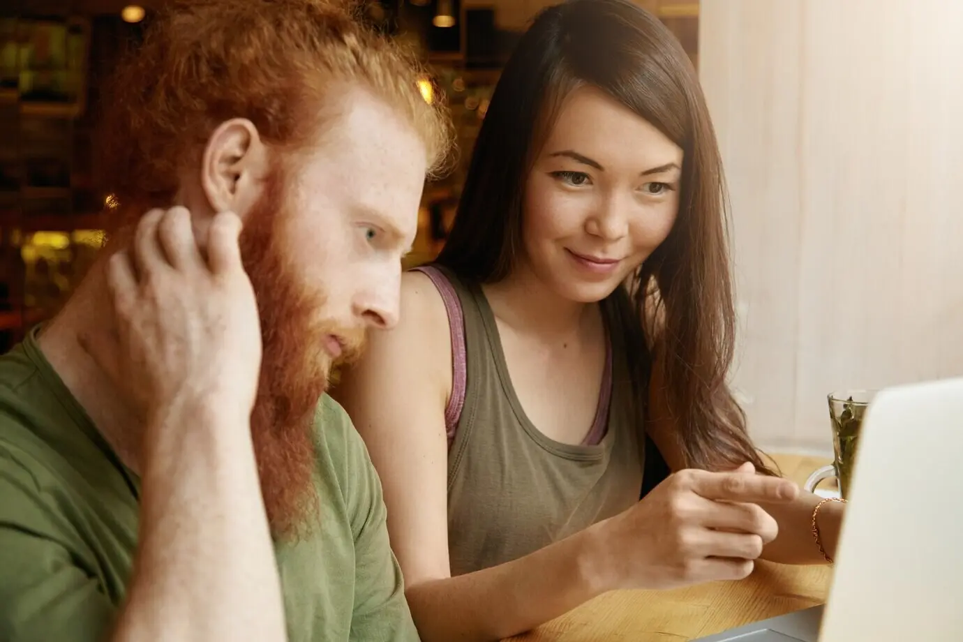 Mujer de cabello castaño y hombre pelirrojo sentados en un café.
